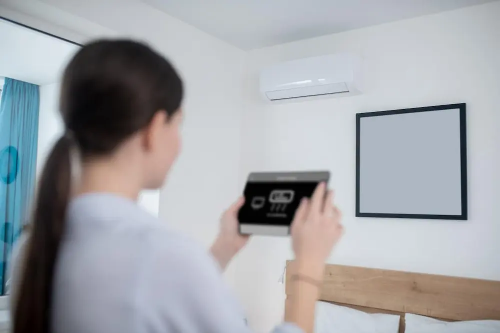 mujer encendiendo aire acondicionado con tablet
