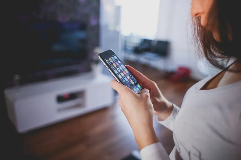 Mujer controlando un aire acondicionado con WiFi con el teléfono móvil